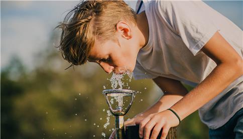 young guy drinking water from a little fountain